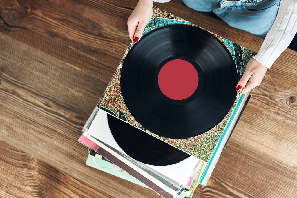 Playing vinyl records. Listening to music from vinyl record player. Retro and vintage music style. Woman holding analog LP record album. Stack of old records. Music collection. Music passion - Foto, Imagen