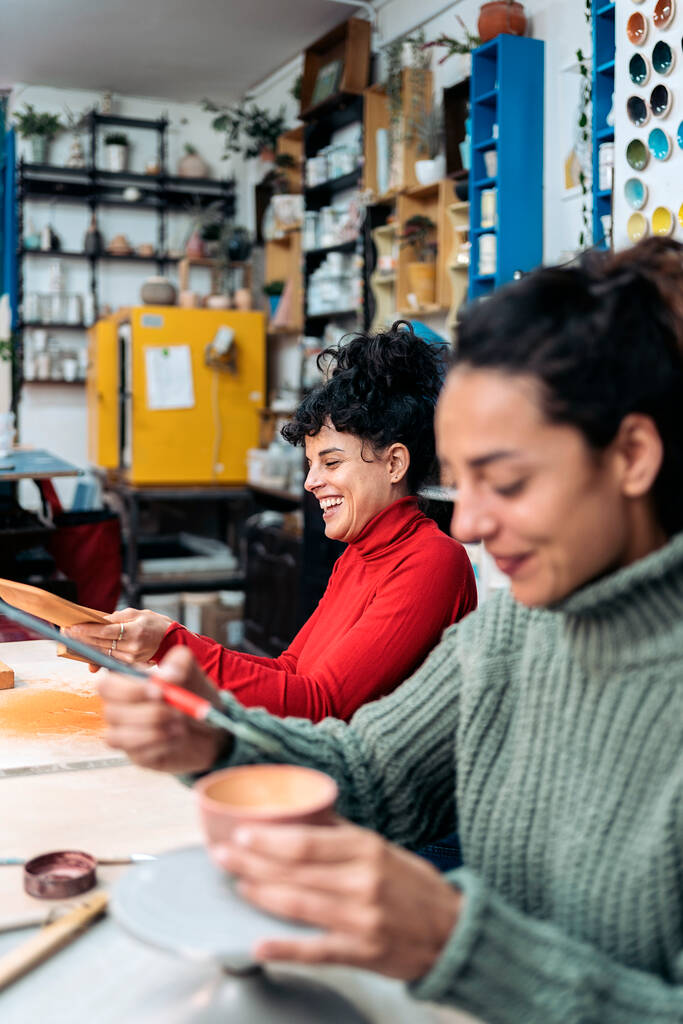 Foto stock di due donne felici che dipingono pezzi di ceramica durante la classe di ceramica. - Foto, immagini