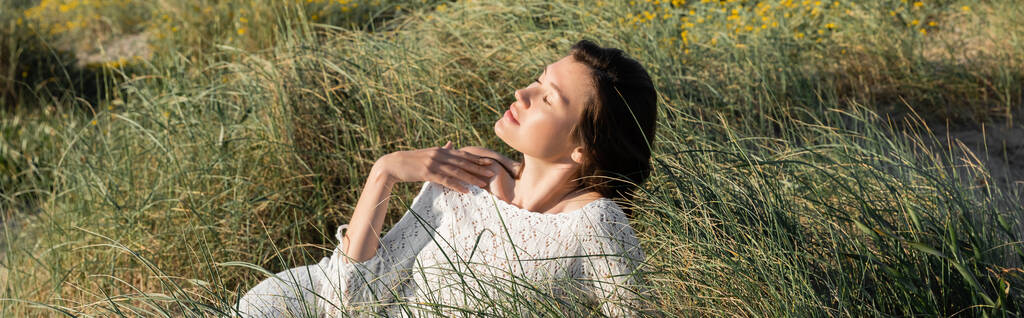 Kumsalda çimlerde dinlenen esmer kadın, afiş.  - Fotoğraf, Görsel