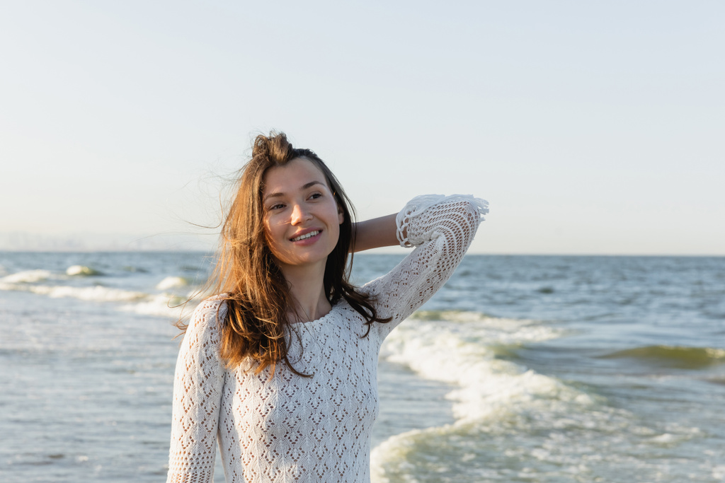 Retrato de una joven morena mirando hacia otro lado cerca del mar borroso  - Foto, Imagen