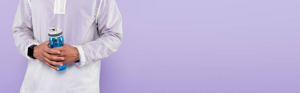 kivágott kilátás afro-amerikai férfi divatos sportruházat gazdaság sport palack elszigetelt lila, banner - Fotó, kép