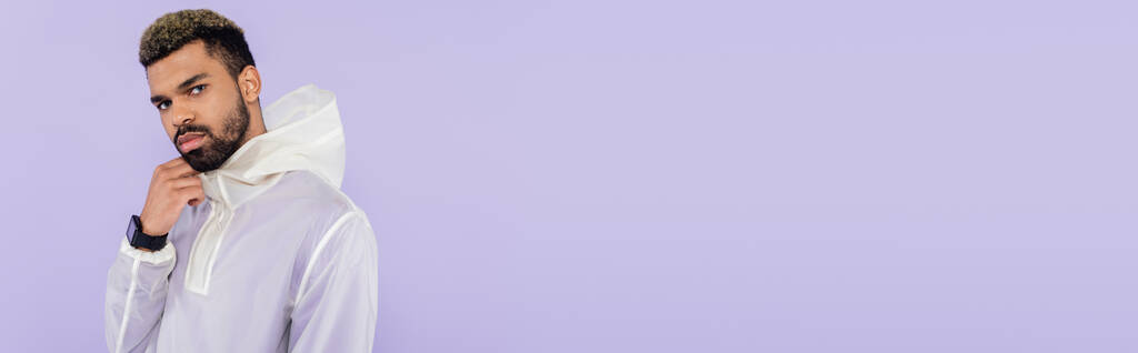 afro-amerikai sportoló stílusos sportruházat néz kamera elszigetelt lila, banner - Fotó, kép