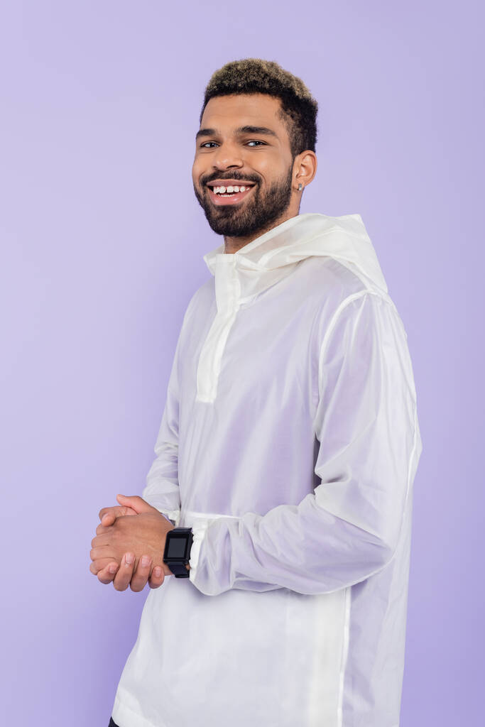 cheerful young african american sportsman with smart watch posing with clenched hands isolated on purple  - Photo, Image