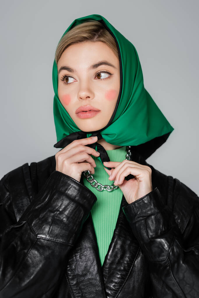femme avec maquillage attachant le mouchoir vert et regardant loin isolé sur gris - Photo, image