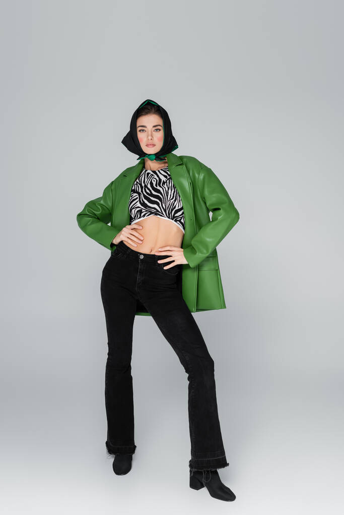 teljes hosszúságú kilátás divatos nő fekete kendő és zöld kabát szürke háttér - Fotó, kép