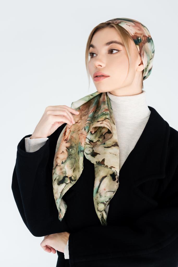 stijlvolle vrouw in hoofddoek en zwarte jas weg te kijken geïsoleerd op grijs - Foto, afbeelding