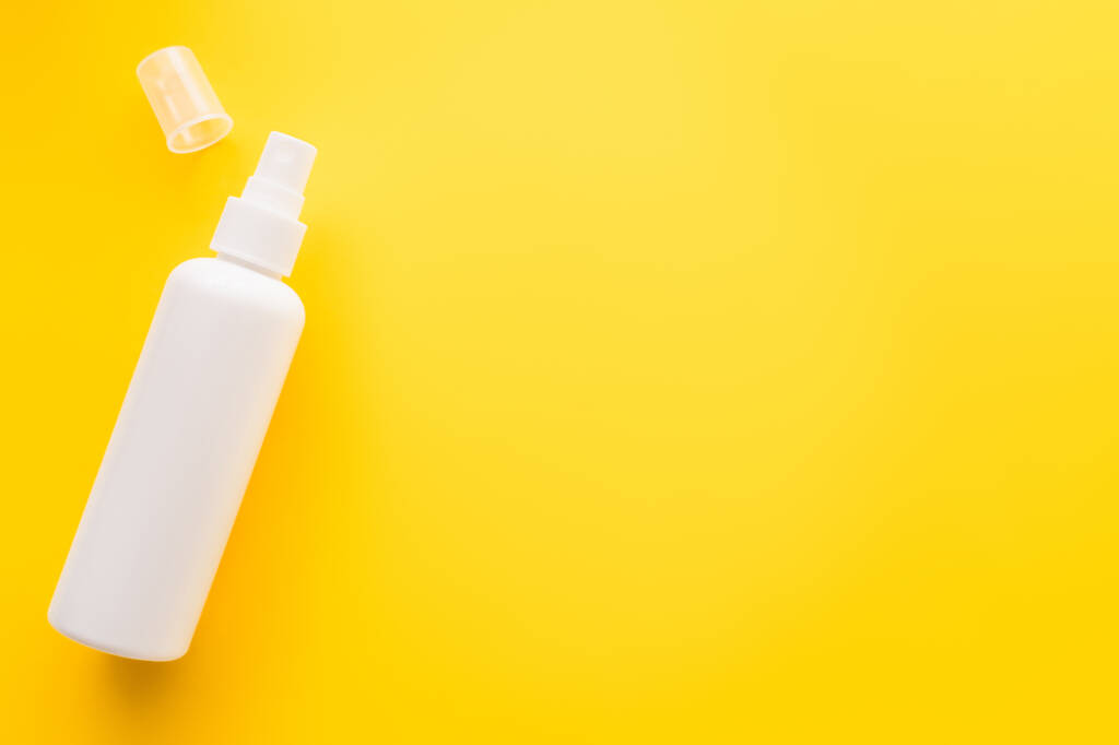 Верхний вид солнцезащитного крема с крышкой на желтой поверхности  - Фото, изображение