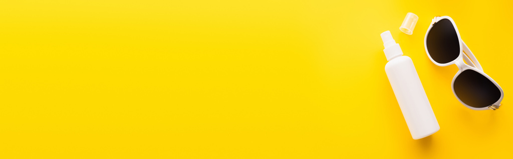 Vista superior de bloqueador solar y gafas de sol en la superficie amarilla, pancarta  - Foto, imagen