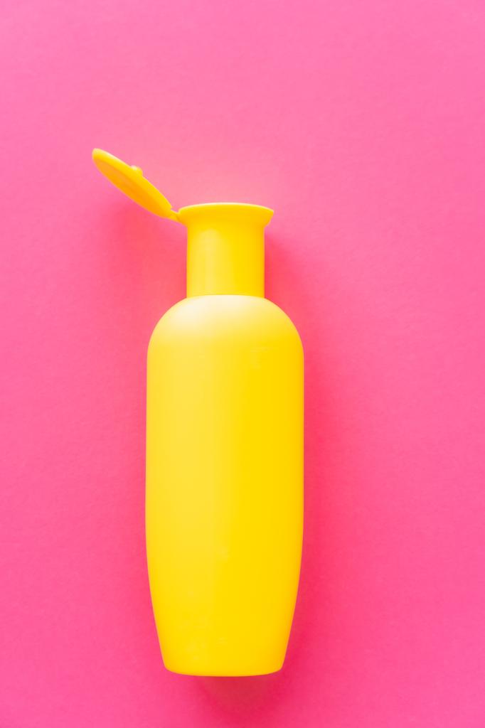 Top näkymä keltainen pullo aurinkovoidetta vaaleanpunainen pinta - Valokuva, kuva