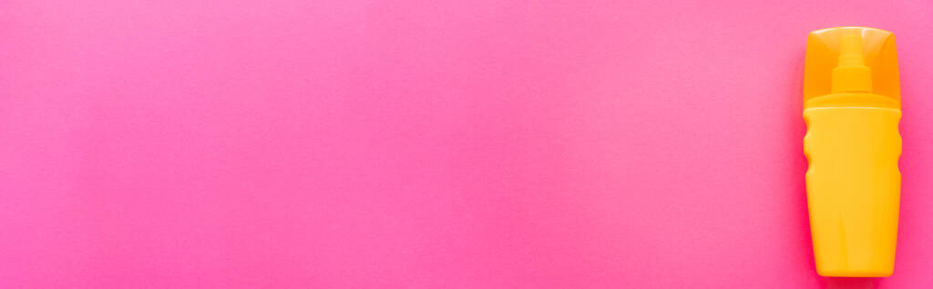 Vista dall'alto della bottiglia arancione di crema solare sulla superficie rosa con spazio per la copia, banner  - Foto, immagini