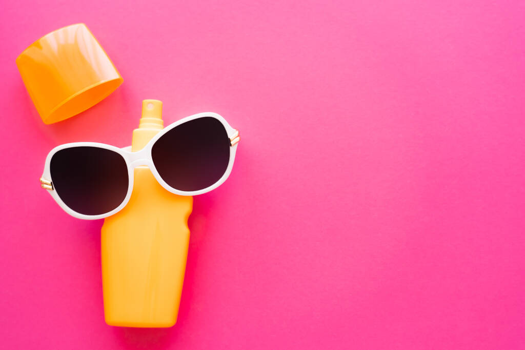 Вид зверху сонцезахисні окуляри на сонцезахисному кремі на рожевій поверхні
 - Фото, зображення