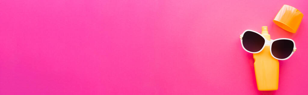 ピンクの表面に日焼け止めとサングラスのトップビュー、バナー  - 写真・画像