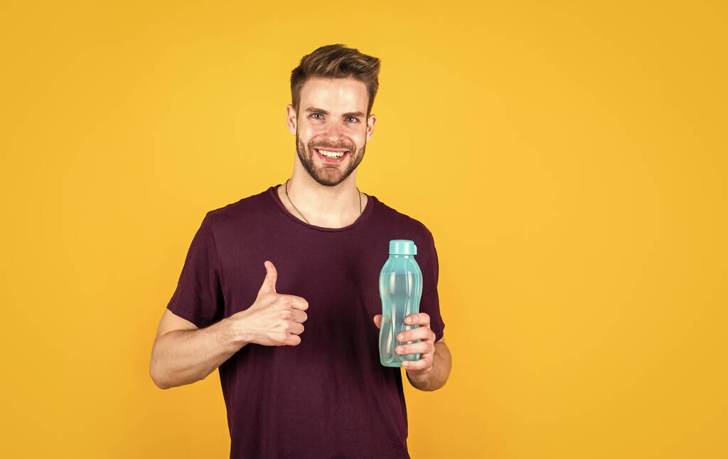 thumb up. man relax after sport. feeling thirsty. keep water balance in body. hydration. handsome young man drink water. casual summer fashion style. male beauty and fashion. guy hold plastic bottle. - Photo, Image