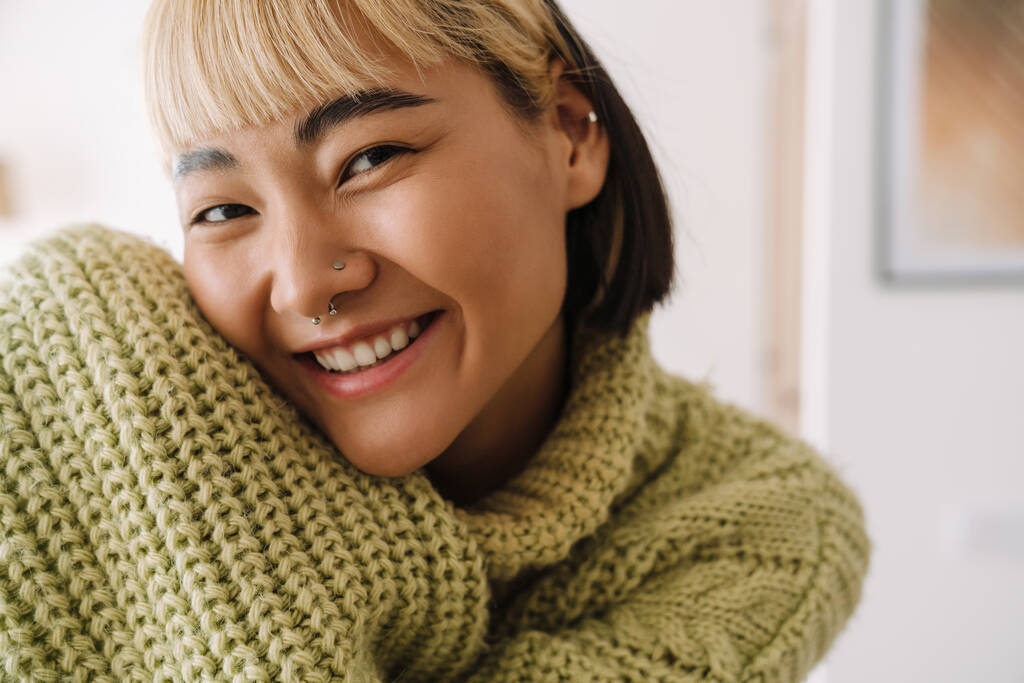 Asijské dospívající dívka s piercing s úsměvem na kameru při odpočinku doma - Fotografie, Obrázek