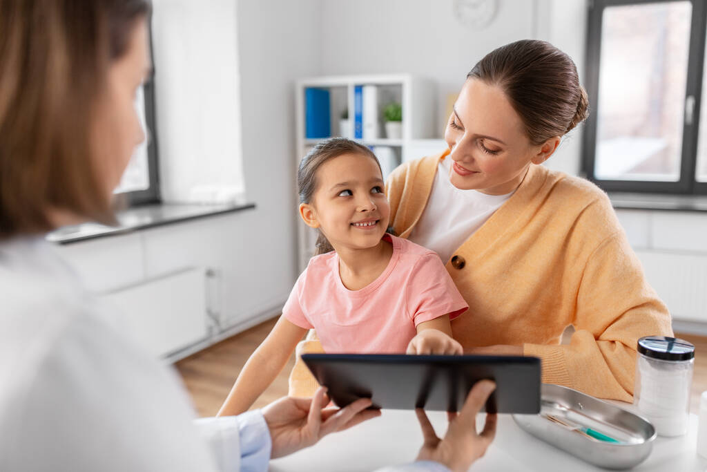concept de médecine, de soins de santé et de pédiatrie - mère avec petite fille et médecin montrant un ordinateur tablette à la clinique - Photo, image