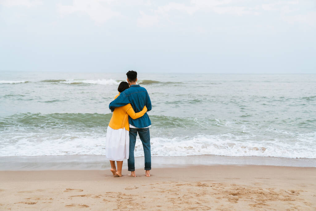 Multiracial couple hugging during walking on summer beach - Photo, Image