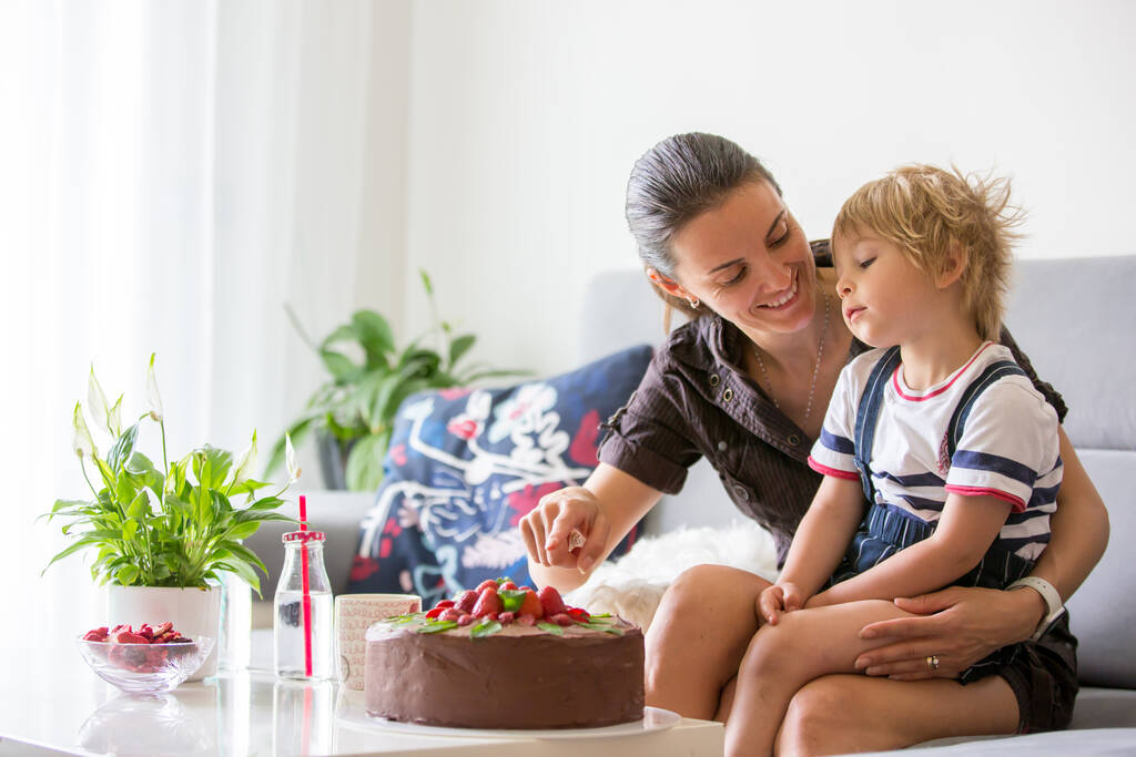 Mother and child, toddler boy, watching movie on a tablet, cake and flowers on the table - Photo, Image
