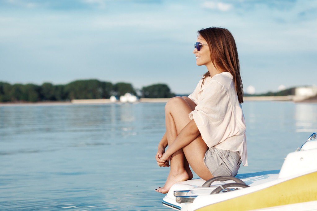 Женщина на лодке счастливо улыбается, глядя на море - Фото, изображение