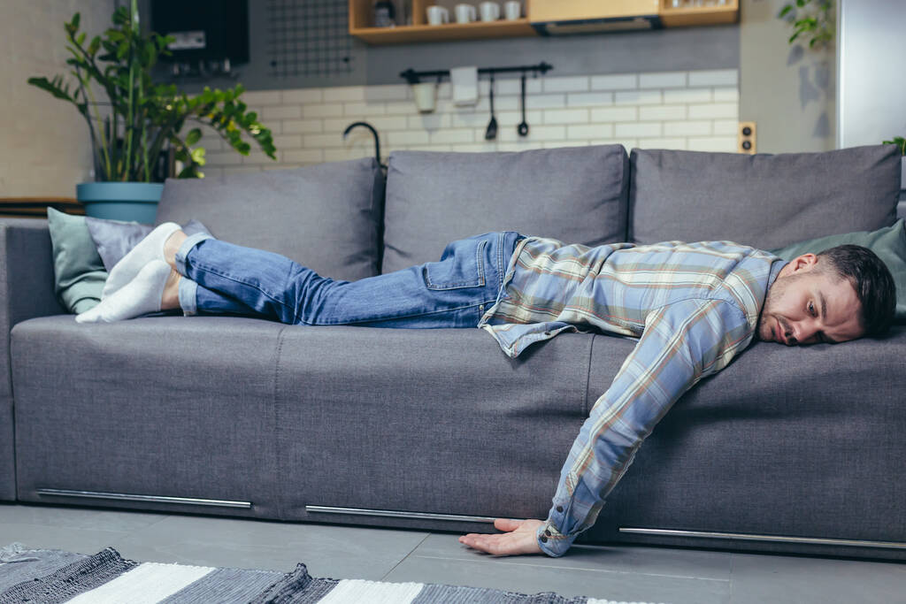 自宅でソファの上で寝る仕事の後に疲れて落ち込んで男 - 写真・画像
