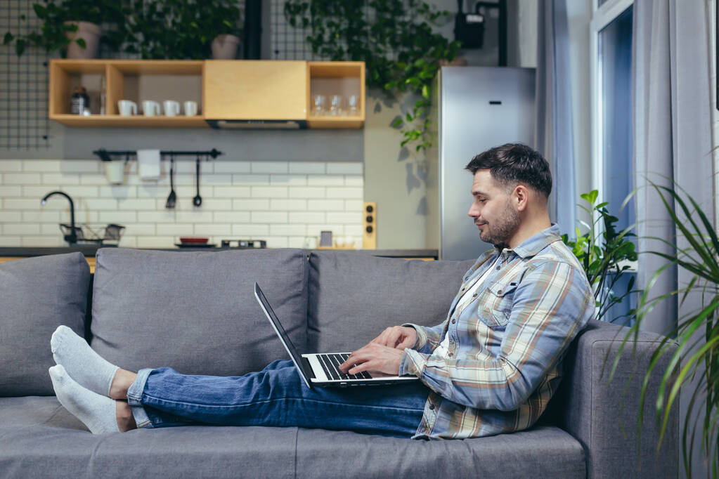 Man at home working sitting on sofa remotely with laptop - Photo, Image