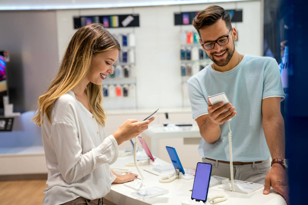 Glückliche junge Leute kaufen neue Smartphones im mobilen Geschäft. Technologie Glücklichkeits-Gerät-Shopping-Konzept - Foto, Bild