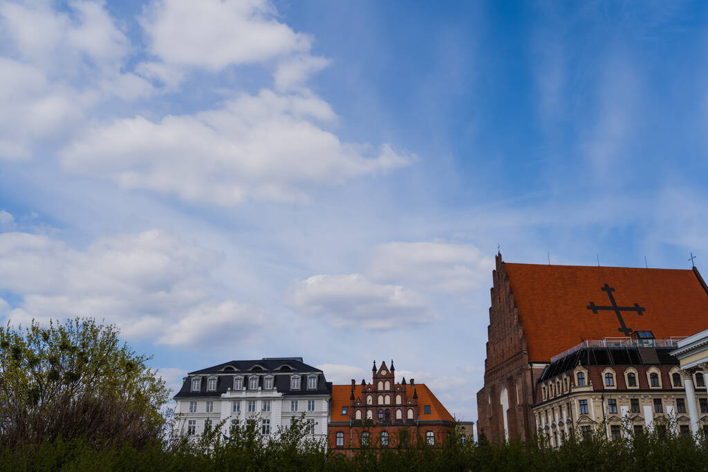 St Dorothea Kilisesi Wroclaw 'da arka planda gökyüzü olan binaların yakınında. - Fotoğraf, Görsel