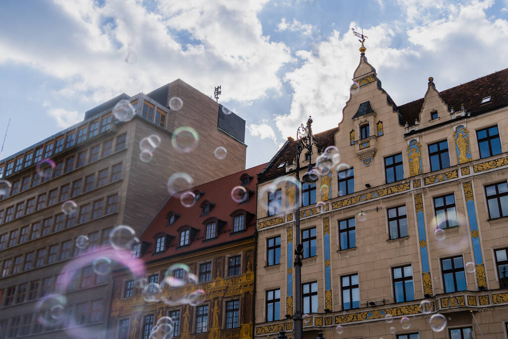 Nízký úhel pohledu na rozmazané mýdlové bubliny a budovy na ulici ve Vratislavi - Fotografie, Obrázek