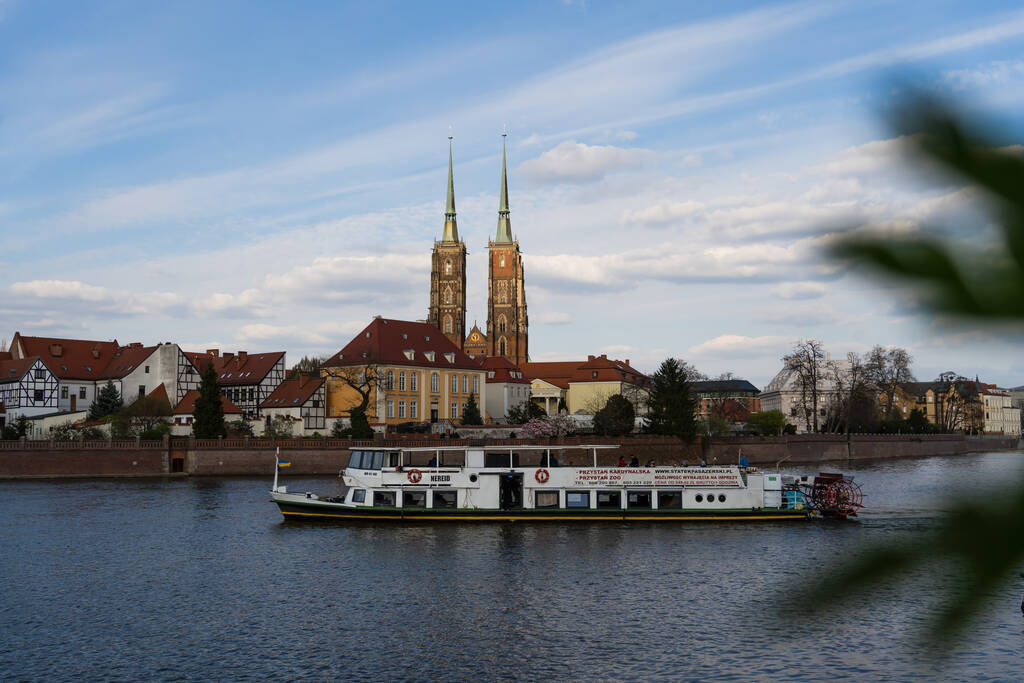 WROCLAW, POLAND - APRIL 18, 2022: Boat on river water with buildings on embankment at background  - Photo, Image