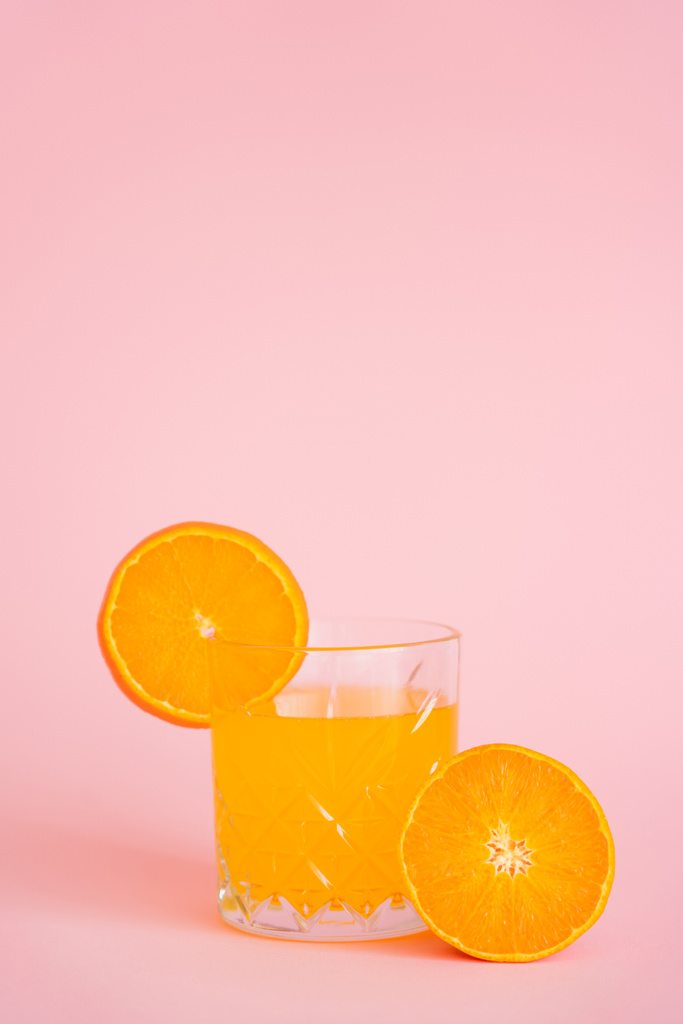 glass of refreshing juice and sliced orange on pink background - Photo, Image