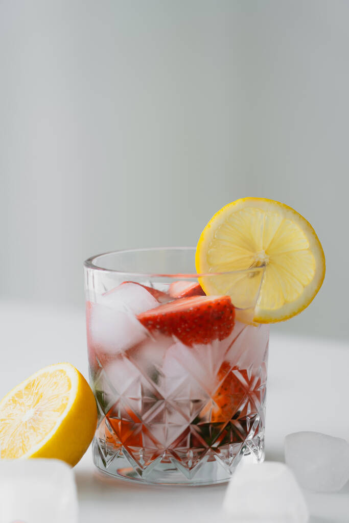 tónico frío con fresas frescas y rodaja de limón en la superficie blanca aislada en gris - Foto, Imagen