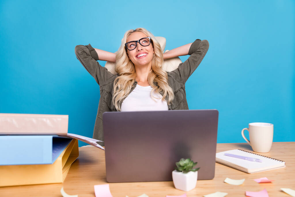 Φωτογραφία πορτρέτο γυναίκα κάθεται στο γραφείο έχοντας διάλειμμα ονειρεύεται διακοπές χαμογελώντας απομονωμένο παστέλ μπλε φόντο χρώμα. - Φωτογραφία, εικόνα