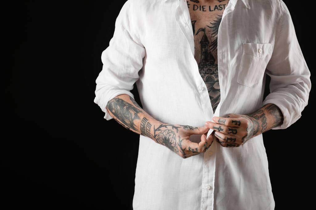 Joven hombre con tatuajes en el cuerpo sobre fondo negro, primer plano - Foto, imagen