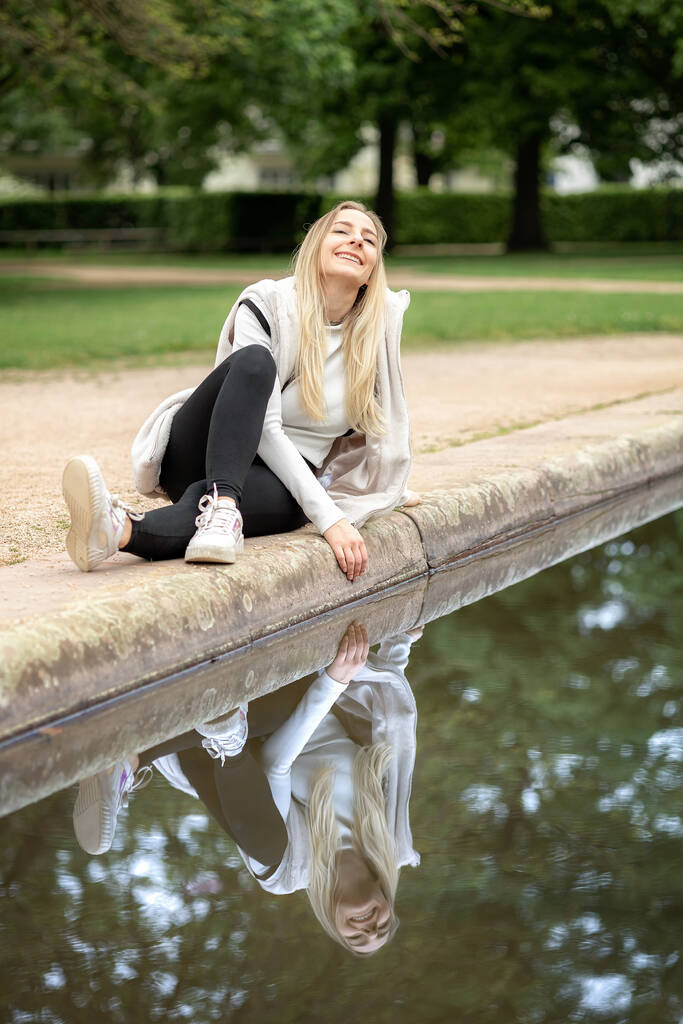 Giovane ragazza vicino a uno stagno con riflesso in acqua - Foto, immagini