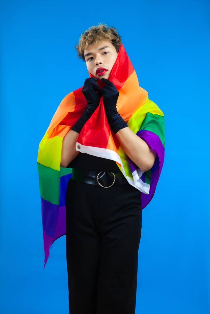 Foto di asiatico gay con orgoglio bandiera arcobaleno isolato colore blu sfondo. Concetti lgbtq e lgbtq + - Foto, immagini