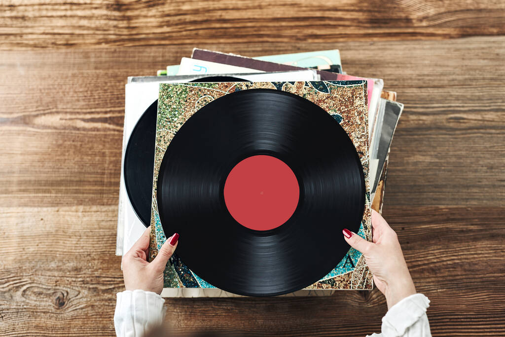 Playing vinyl records. Listening to music from vinyl record player. Retro and vintage music style. Woman holding analog LP record album. Stack of old records. Music collection. Music passion - Photo, image