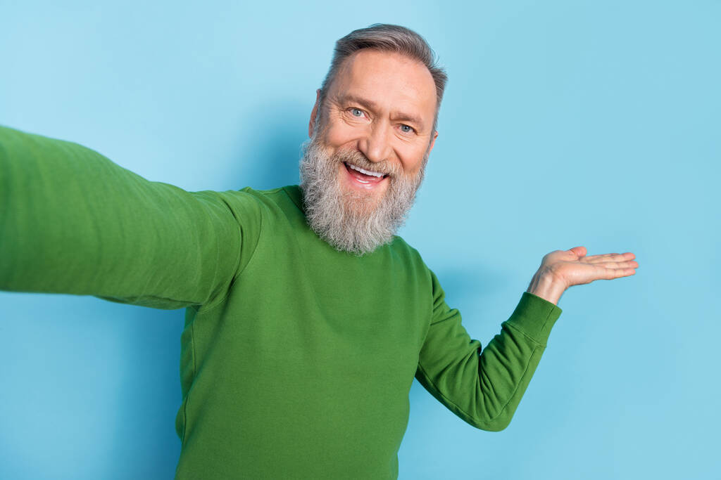 Fotografie pozitivní funky středního věku muž dělat selfie držet dlaň doporučit nákupní prodej izolované modré barvy pozadí. - Fotografie, Obrázek