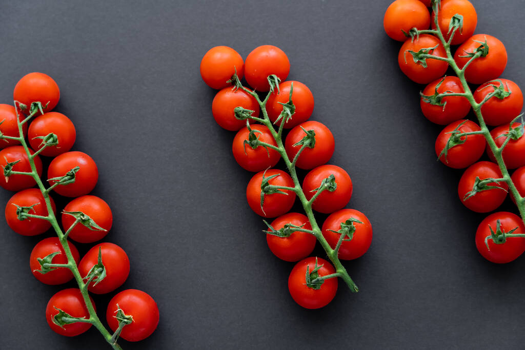 Vista superior de tomates cherry orgánicos sobre ramas sobre fondo negro  - Foto, imagen