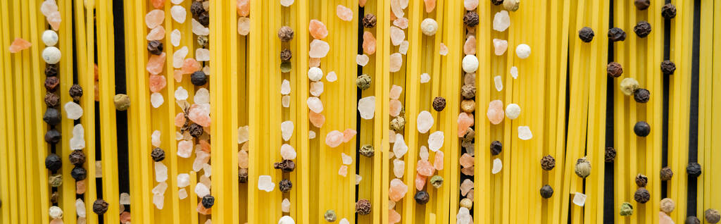 Top kilátás nyers spagetti és fűszerek fekete alapon, banner  - Fotó, kép