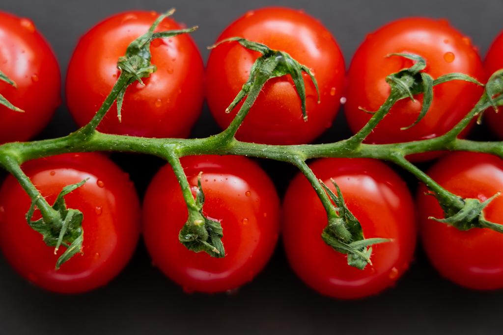 Close-up vista de tomates cereja molhados no fundo preto  - Foto, Imagem