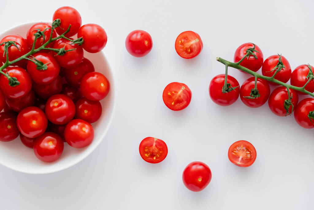 Horní pohled na přírodní cherry rajčata na větvích v misce na bílém pozadí  - Fotografie, Obrázek