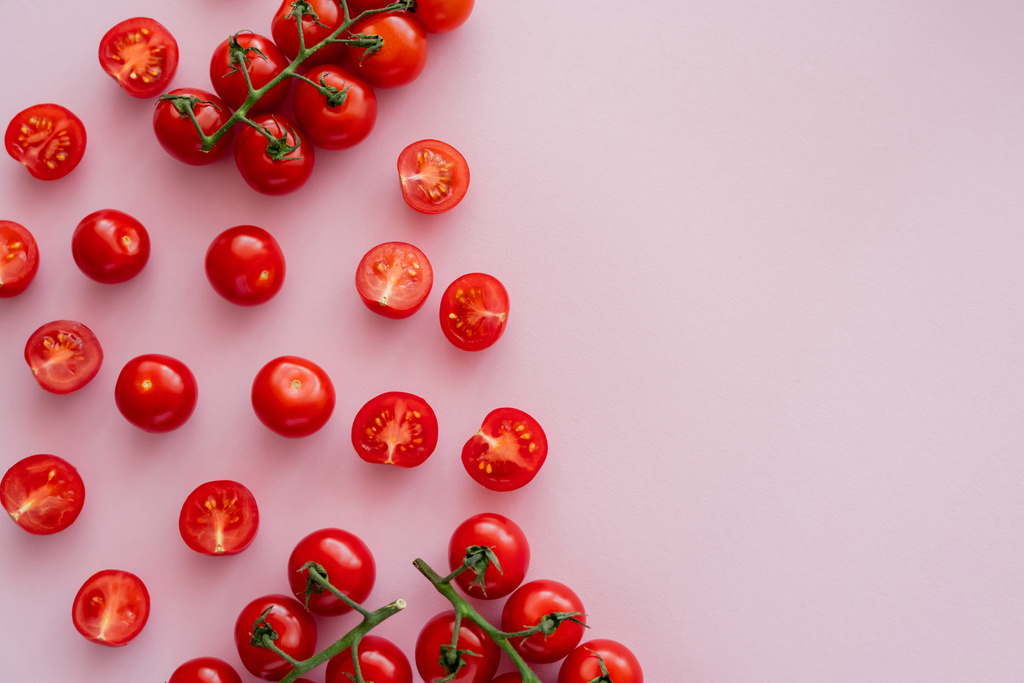 Vista superior de tomates cortados y cherry enteros en superficie rosa con espacio para copiar - Foto, imagen