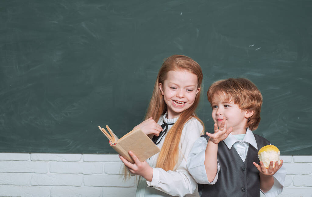 Το παιδί μαθαίνει στην τάξη στο φόντο του μαυροπίνακα. Μαθητές. Χαριτωμένο μικρό παιδί προσχολικής ηλικίας με μικρό κοριτσάκι σε μια τάξη. Μαθητής. Φιλική και φιλική έννοια - Φωτογραφία, εικόνα