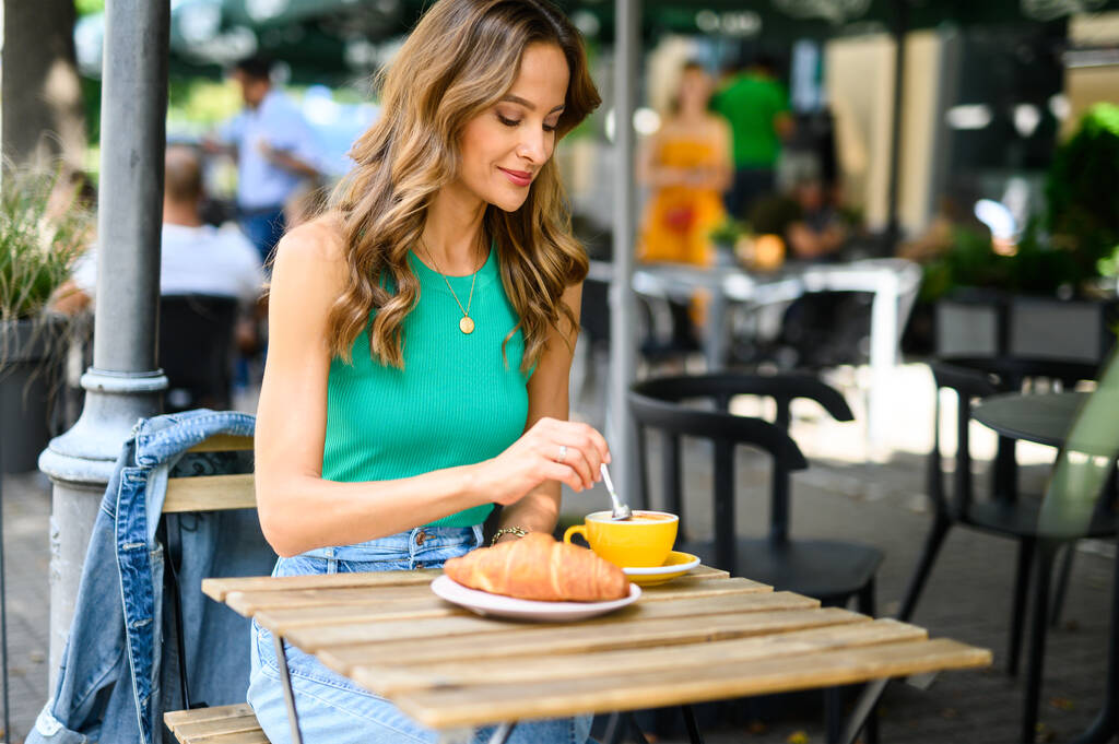 Mujer sonriente desayunando al aire libre en una ciudad - Foto, Imagen