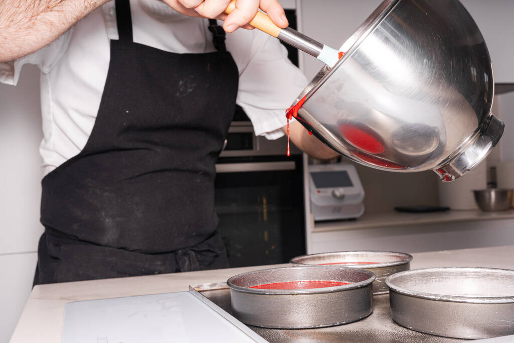 Mãos de um homem cozinhando um bolo de veludo vermelho em casa, adicionando o bolo de esponja nos moldes antes de colocá-lo no forno, trabalhar em casa - Foto, Imagem