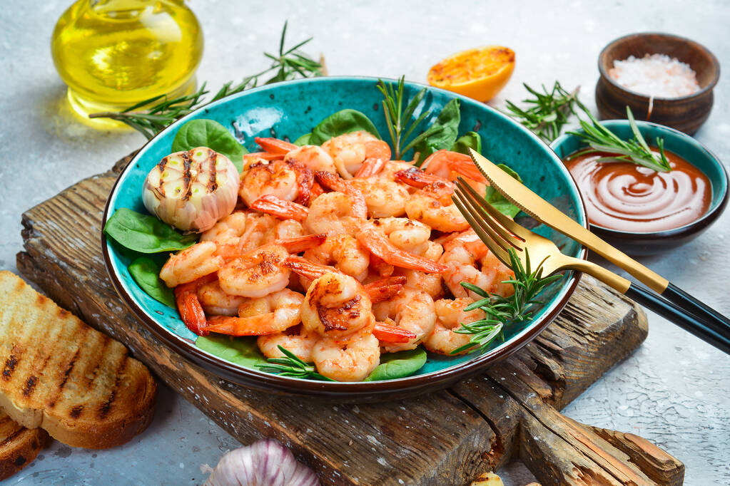 Grilled shrimp with spices and hot chili on a plate. Side view. Seafood. On a stone background. - Photo, Image