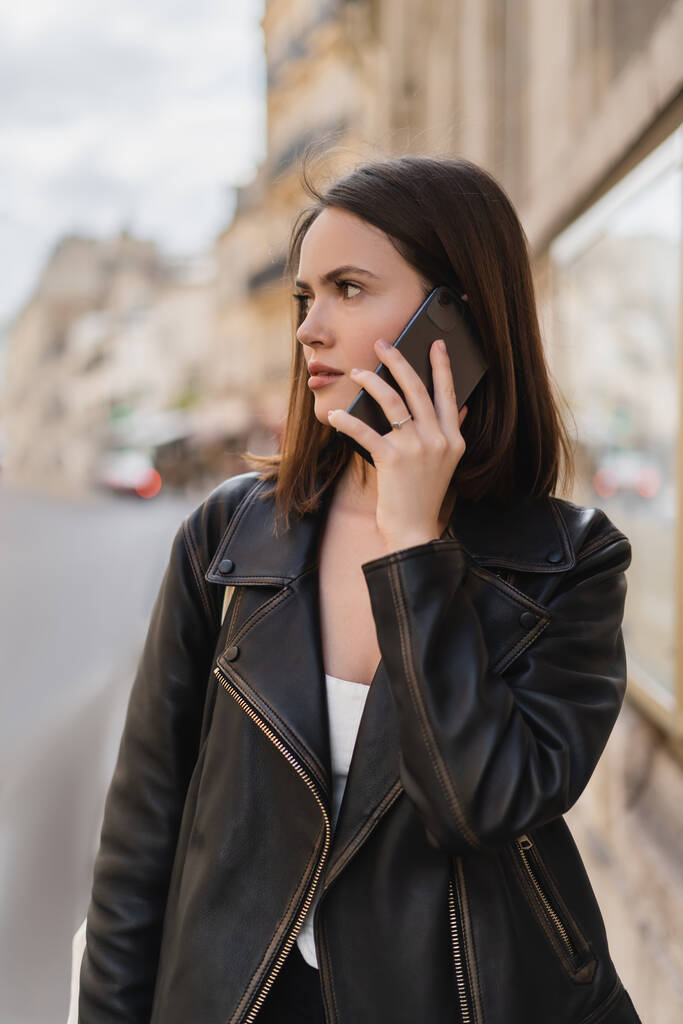 portrait of young woman in stylish jacket talking on smartphone on street in paris  - Photo, Image