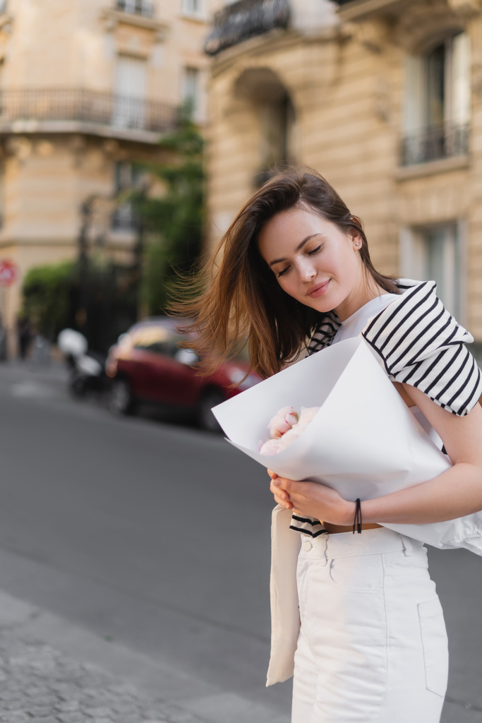 fiatal nő divatos ruhát gazdaság csokor csomagolva papír az utcán Párizsban  - Fotó, kép