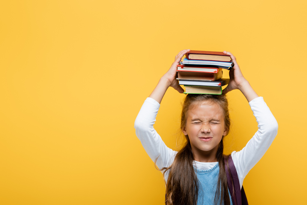 Studentessa positiva che tiene libri e chiude gli occhi isolati sul giallo  - Foto, immagini