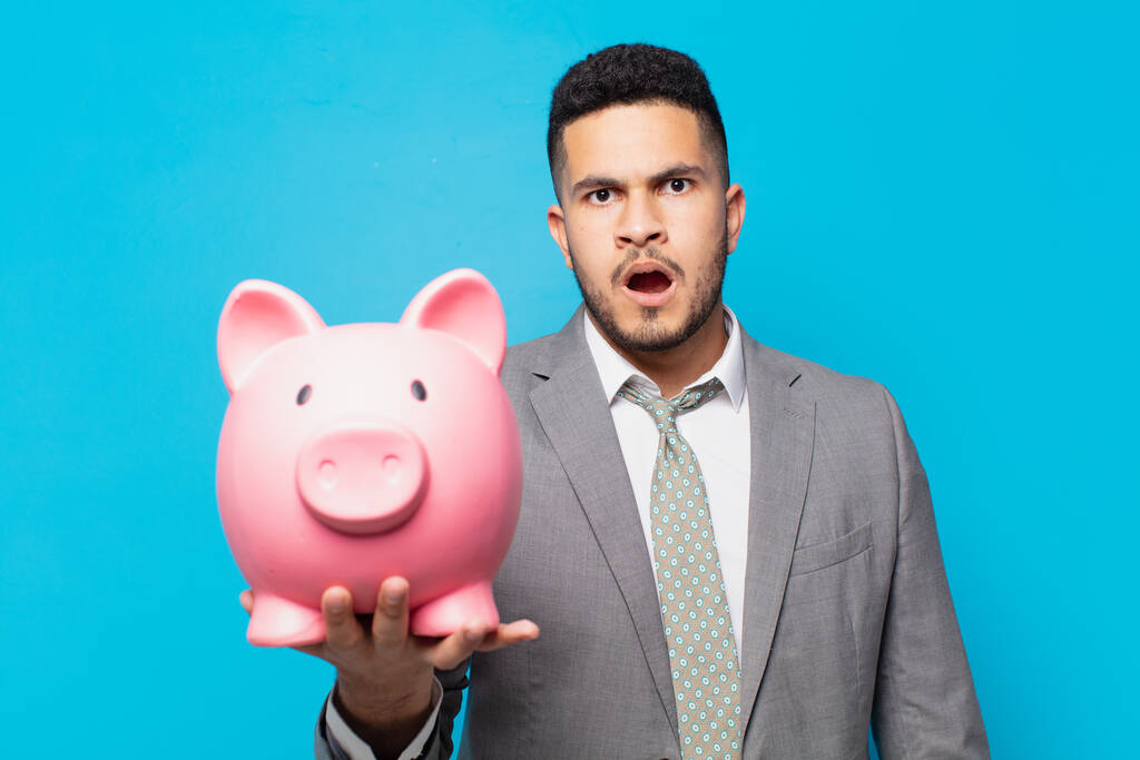 hispanic businessman scared expression and holding a piggy bank - Fotoğraf, Görsel
