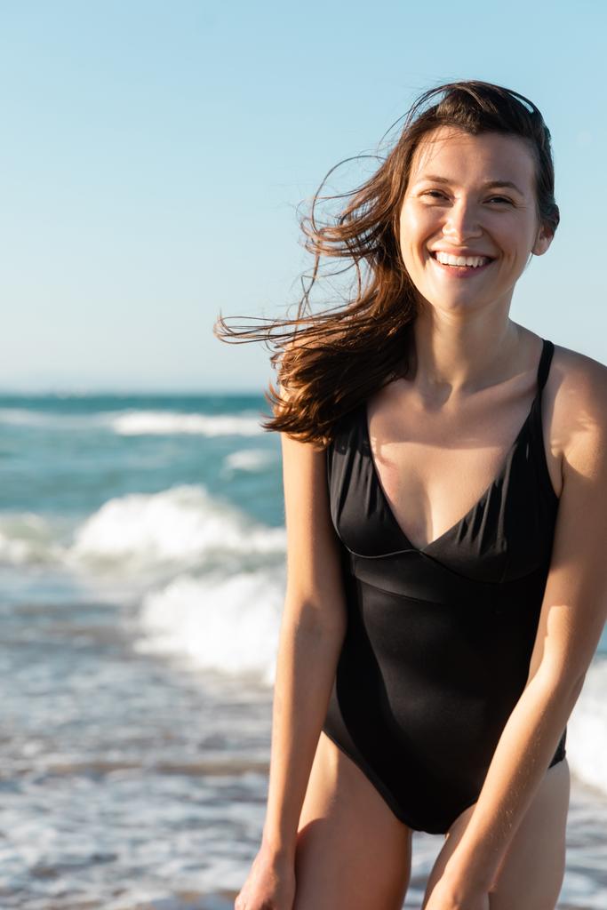πορτρέτο της ευτυχισμένης γυναίκας σε μαύρο μαγιό κοντά στη θάλασσα - Φωτογραφία, εικόνα